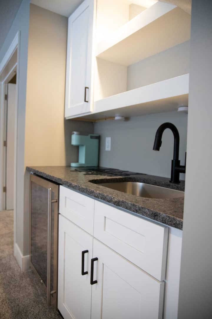 Modern kitchen with white cabinetry, black faucet, and granite countertop in Livingston Homes model.