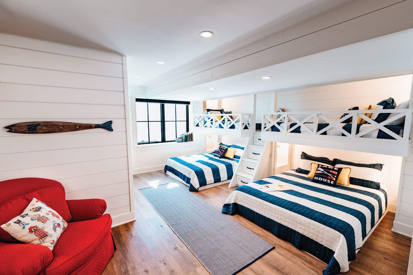 Bright coastal-themed bedroom featuring bunk beds, a lounge area, and large windows with ocean views.
