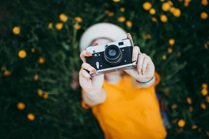 Ragazza con macchina fotografica compatta in un campo di fiori