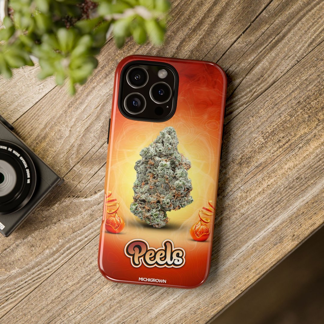 Red phone case with cannabis bud graphic and PEELS logo on wooden surface.