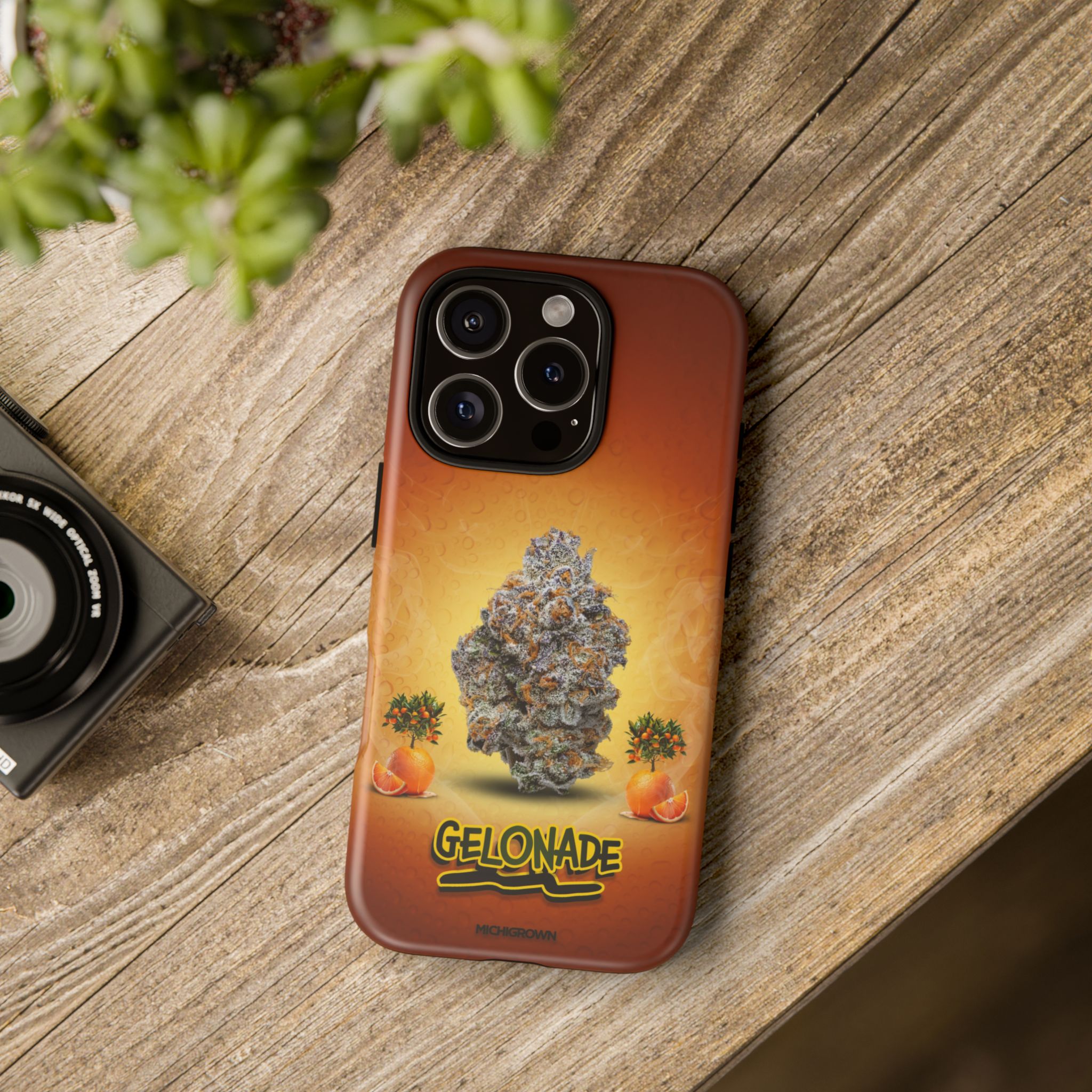Phone case featuring cannabis bud and orange graphics on a wooden surface.