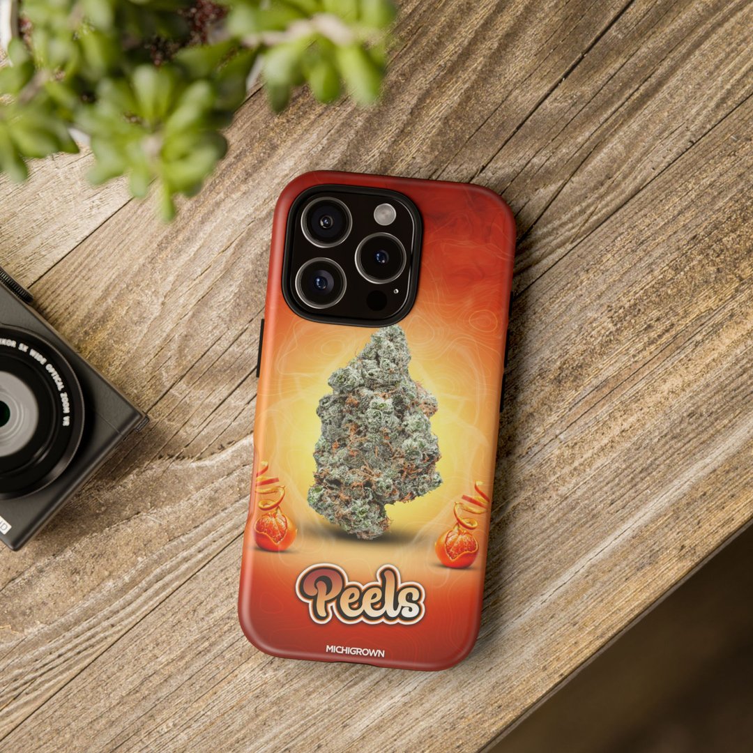 Phone case with cannabis leaf design and Peels logo on wooden surface.