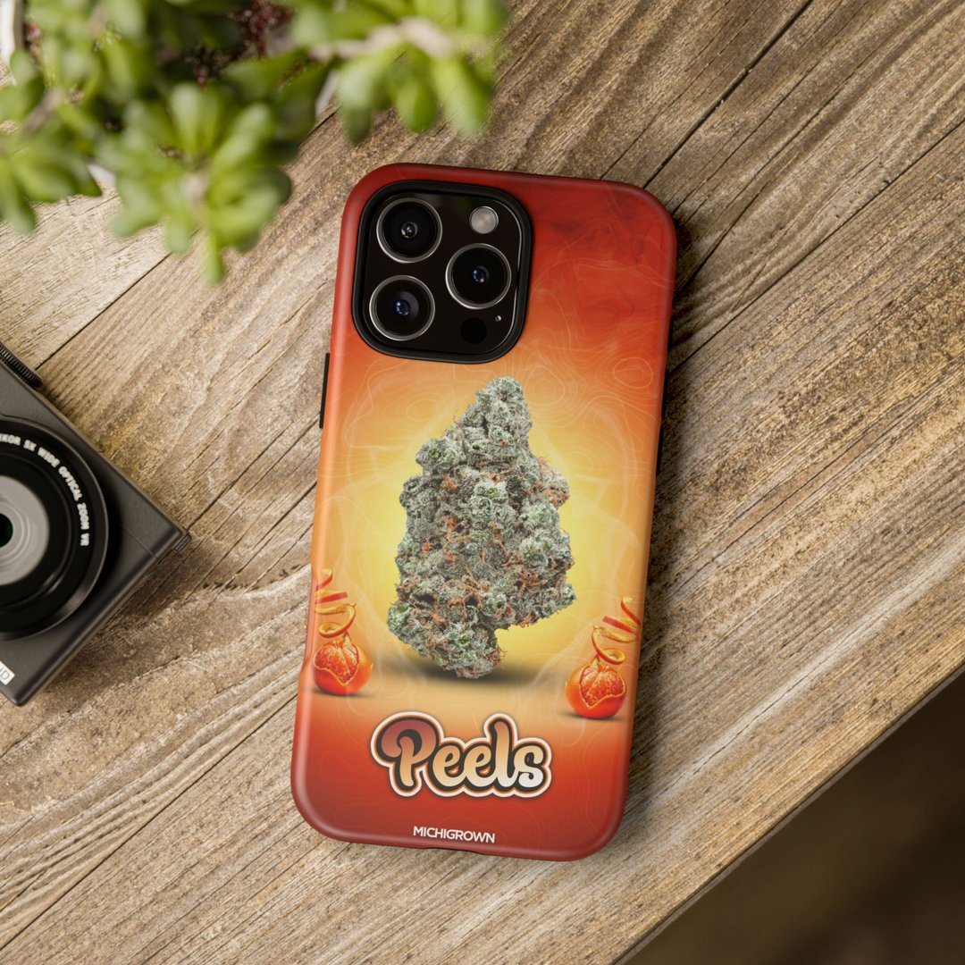 Phone case featuring cannabis bud design and PEELS logo on wooden surface.