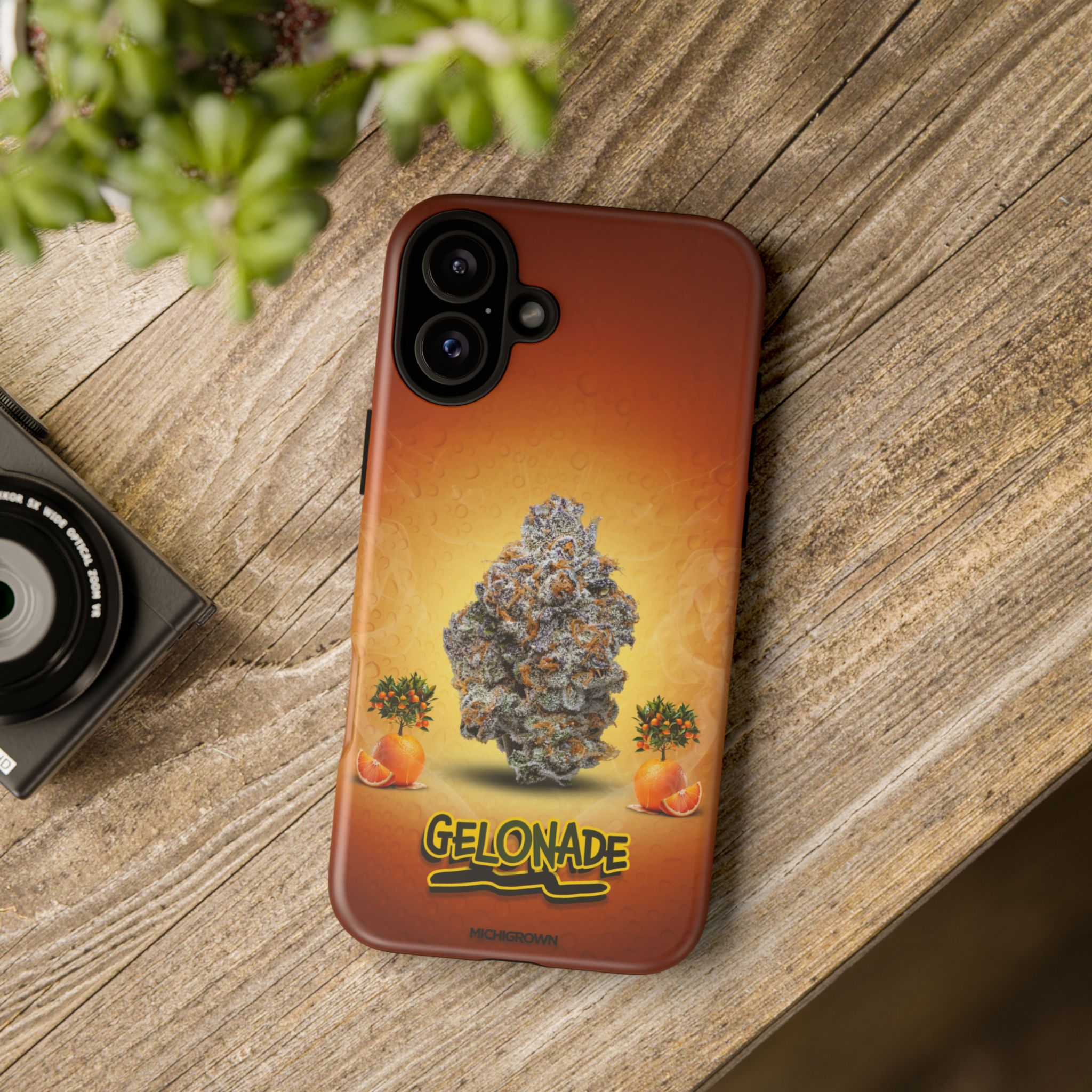 Phone case featuring cannabis bud and orange graphics on a wooden surface.