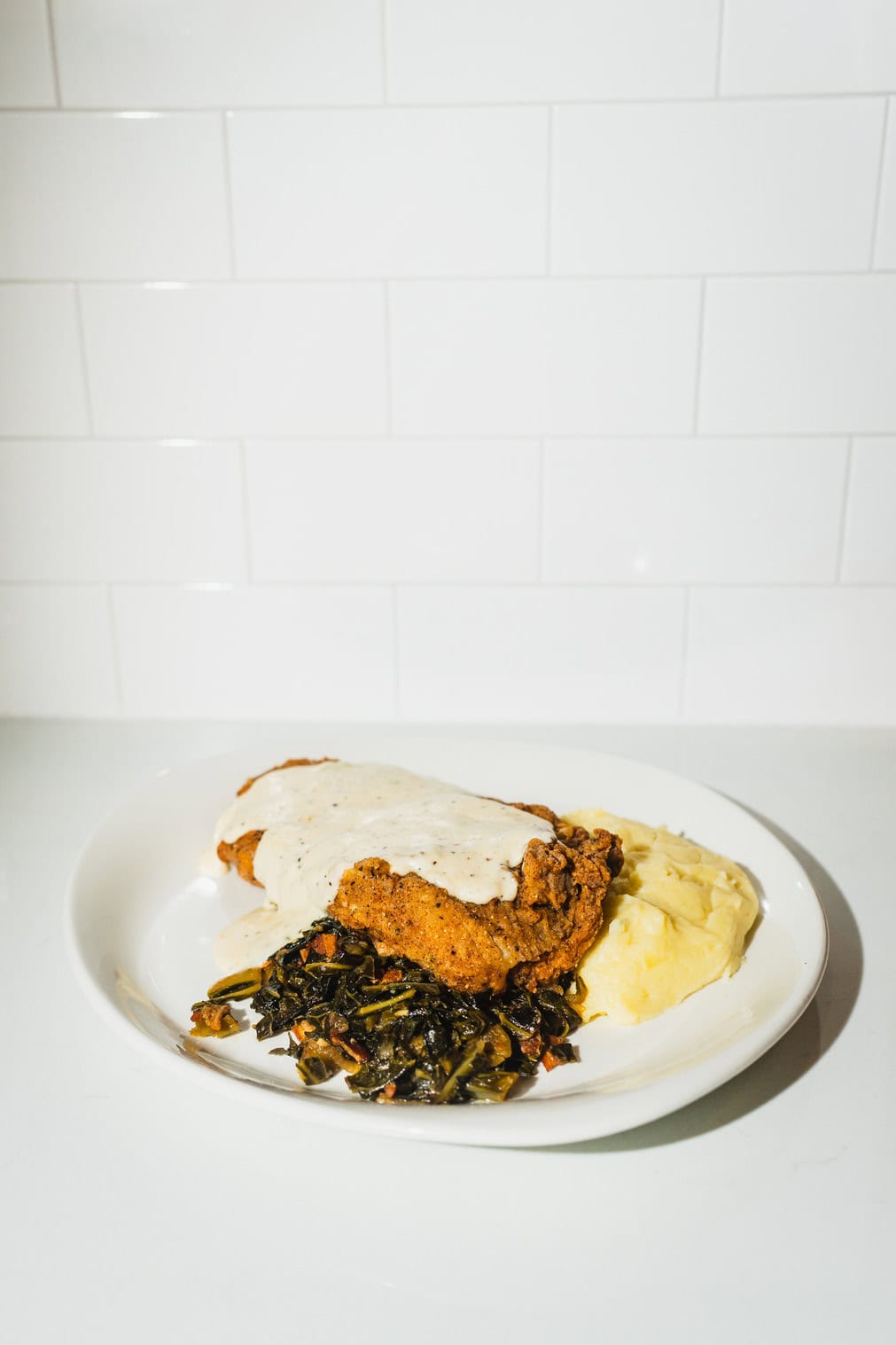 Chicken-fried steak with mashed potatoes, greens, and gravy.