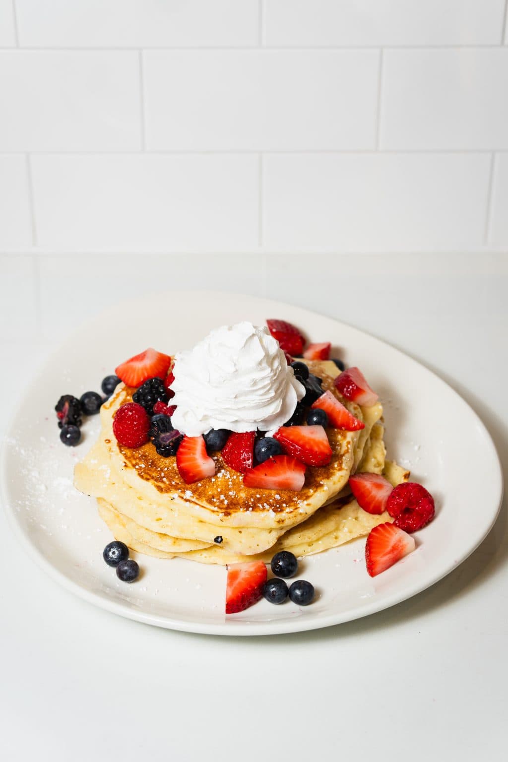 Delicious berry pancake topped with whipped cream and fresh strawberries, blueberries, and raspberr.