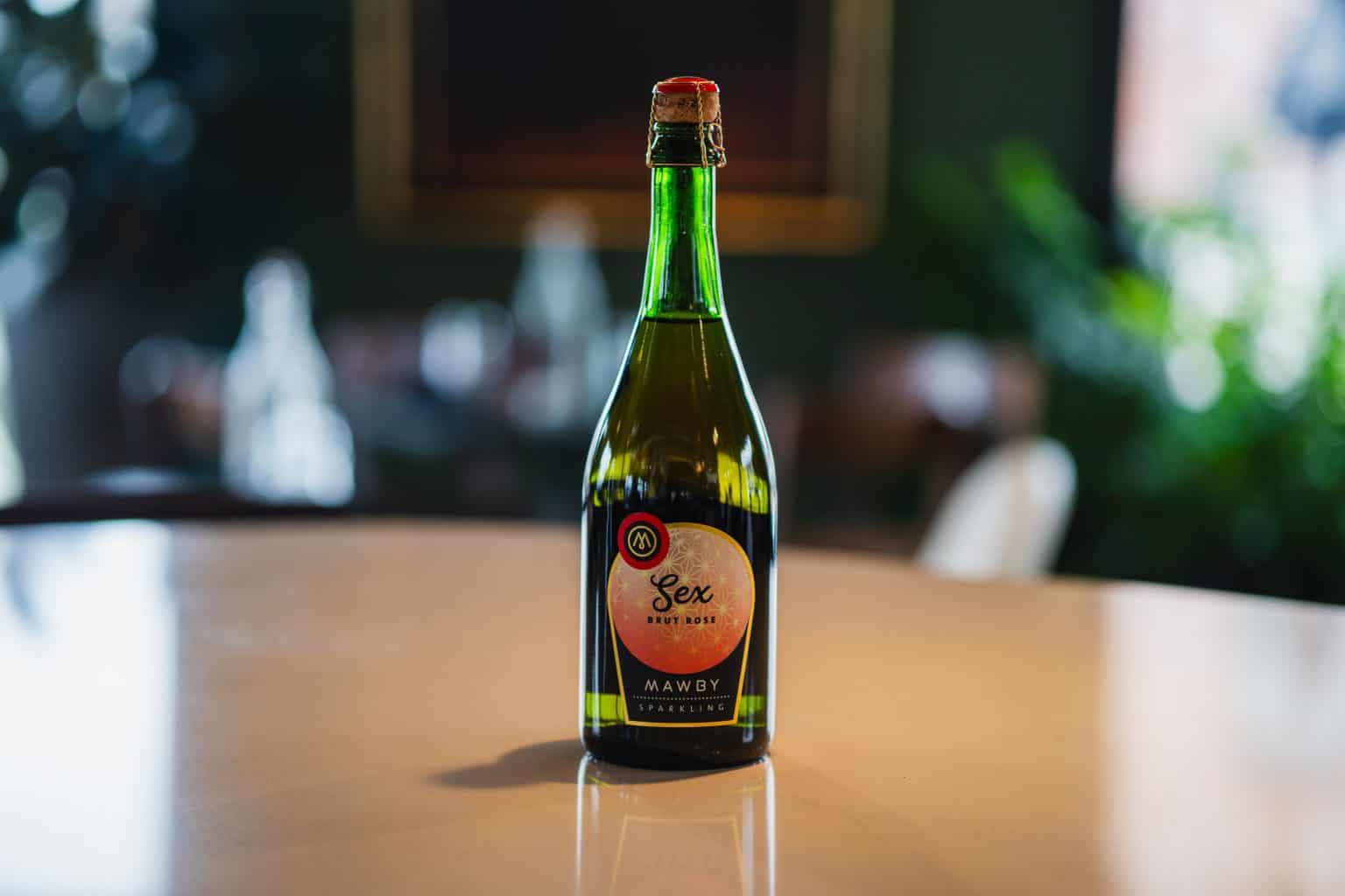 Unique green glass bottle labeled "Sex" on a wooden table in a cozy setting.