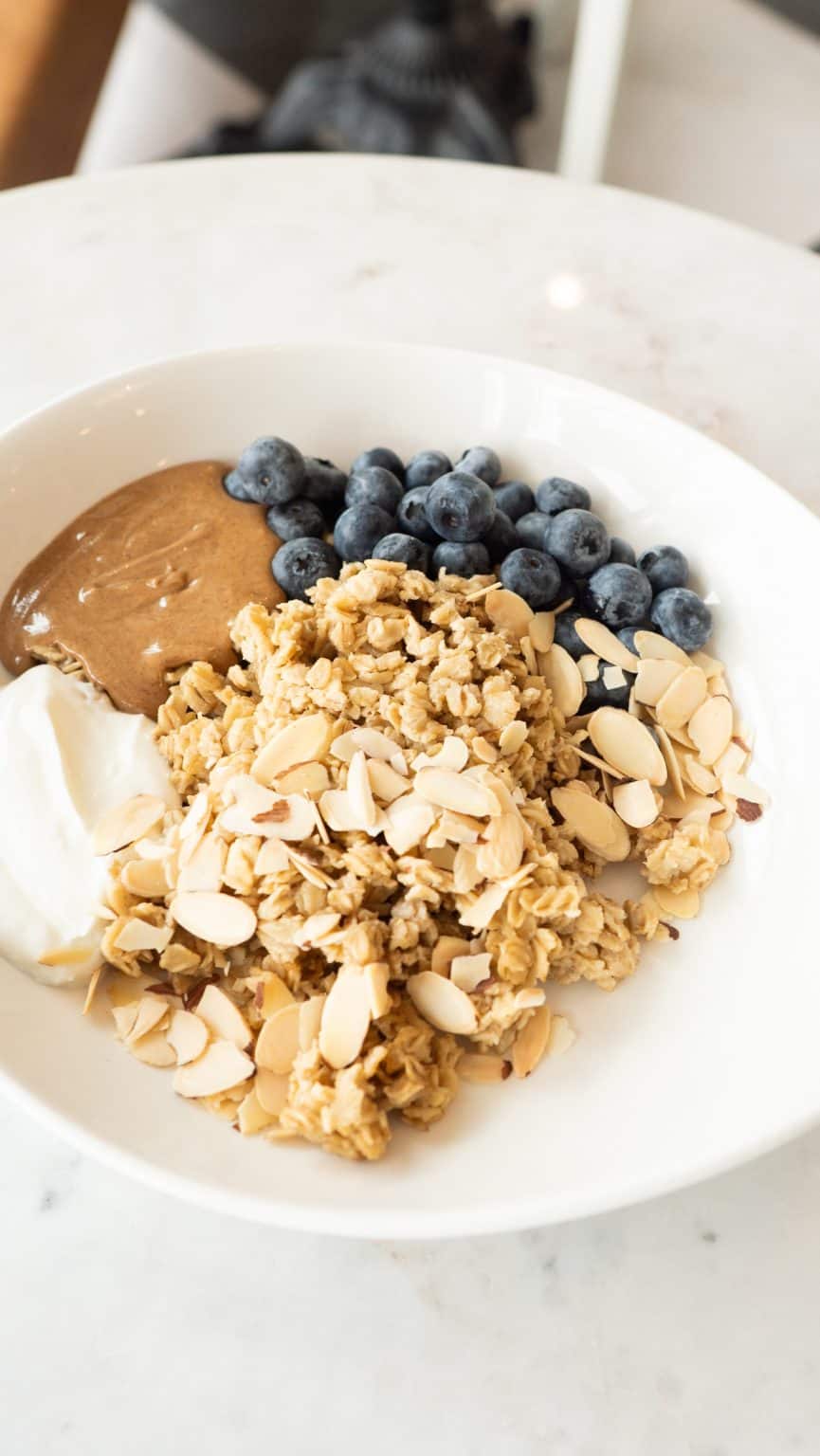 Delicious dessert bowl with blueberries, chocolate, and granola on a white plate.