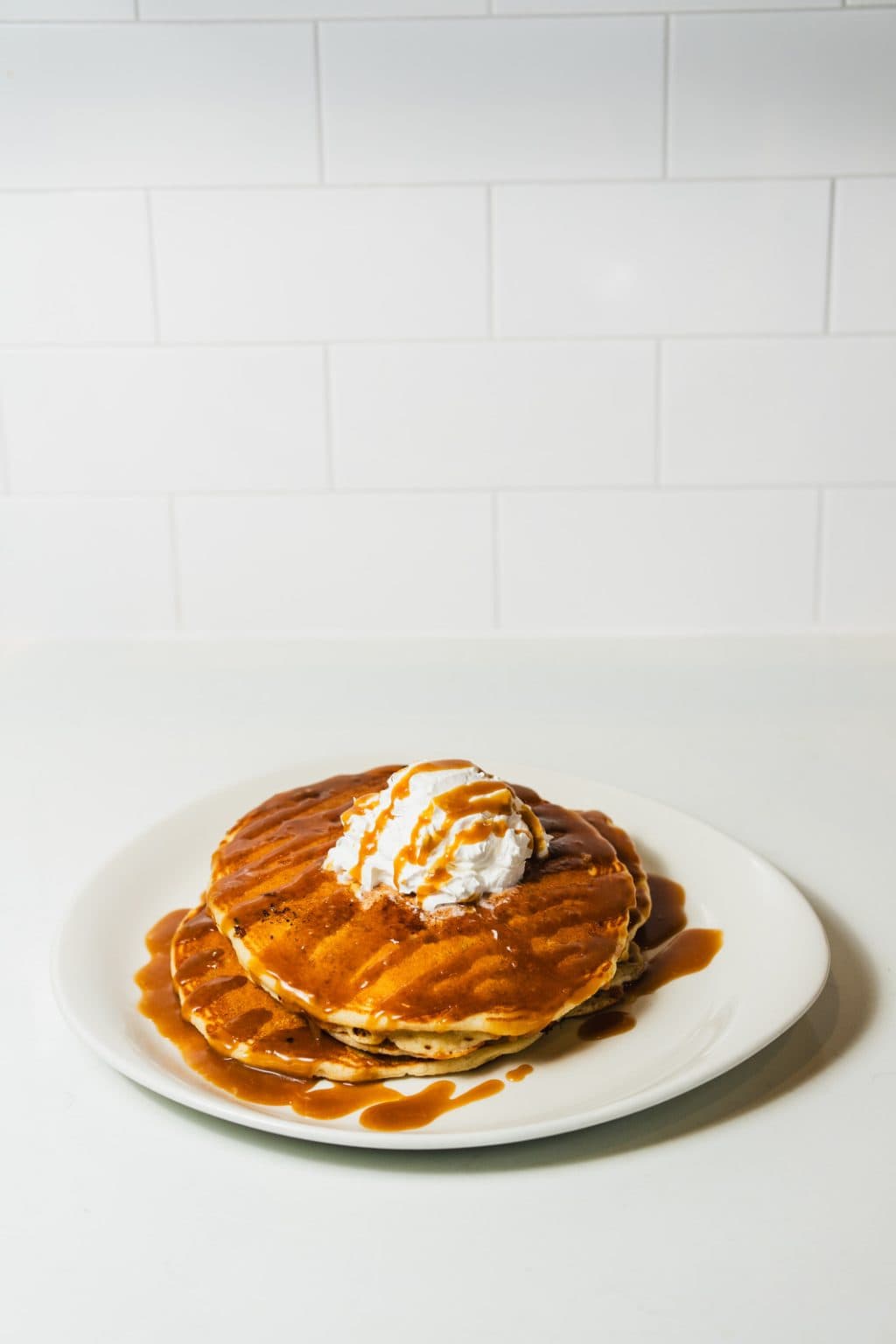 Stack of pancakes topped with whipped cream.