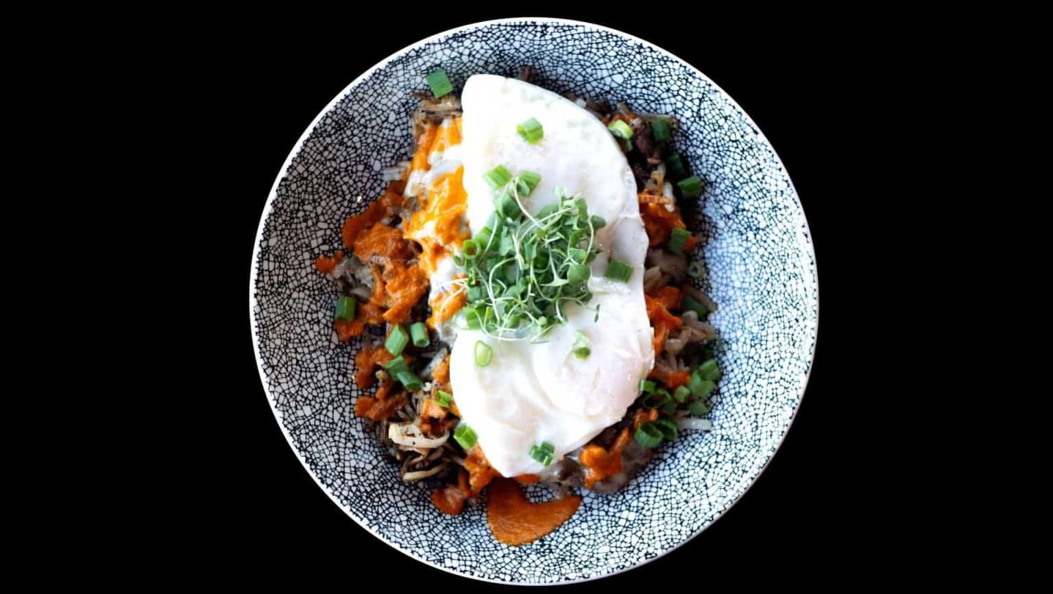 Vegetarian chili served with sour cream and green onions in a textured bowl.