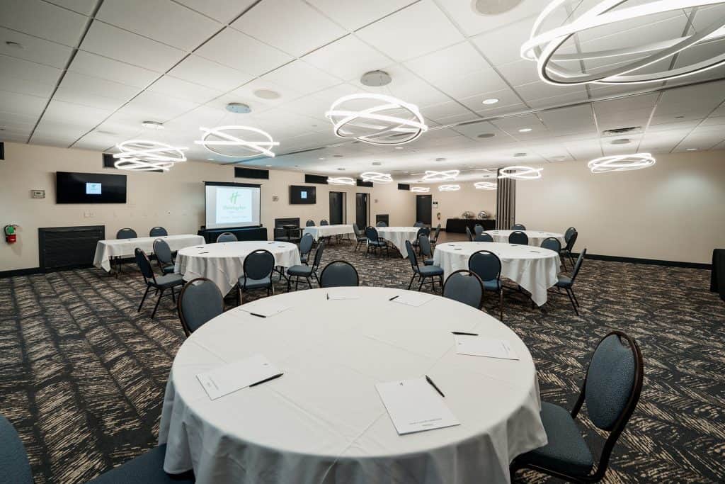 Private event venue with round tables, presentation screens, and contemporary decor.