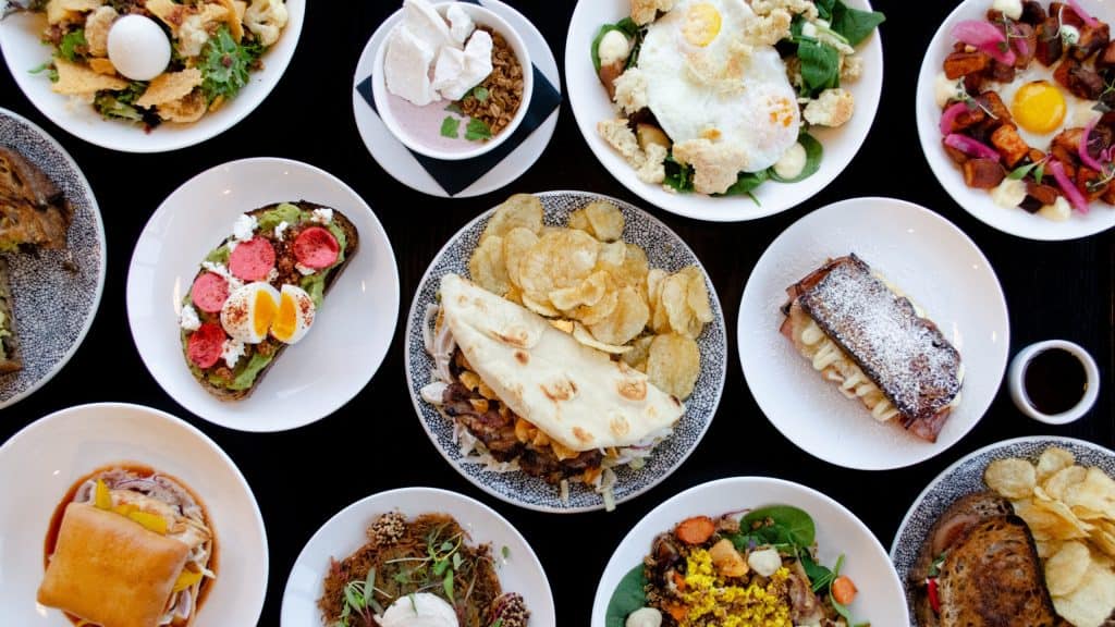 Colorful assortment of gourmet dishes including salads, desserts, and main courses on elegant white.