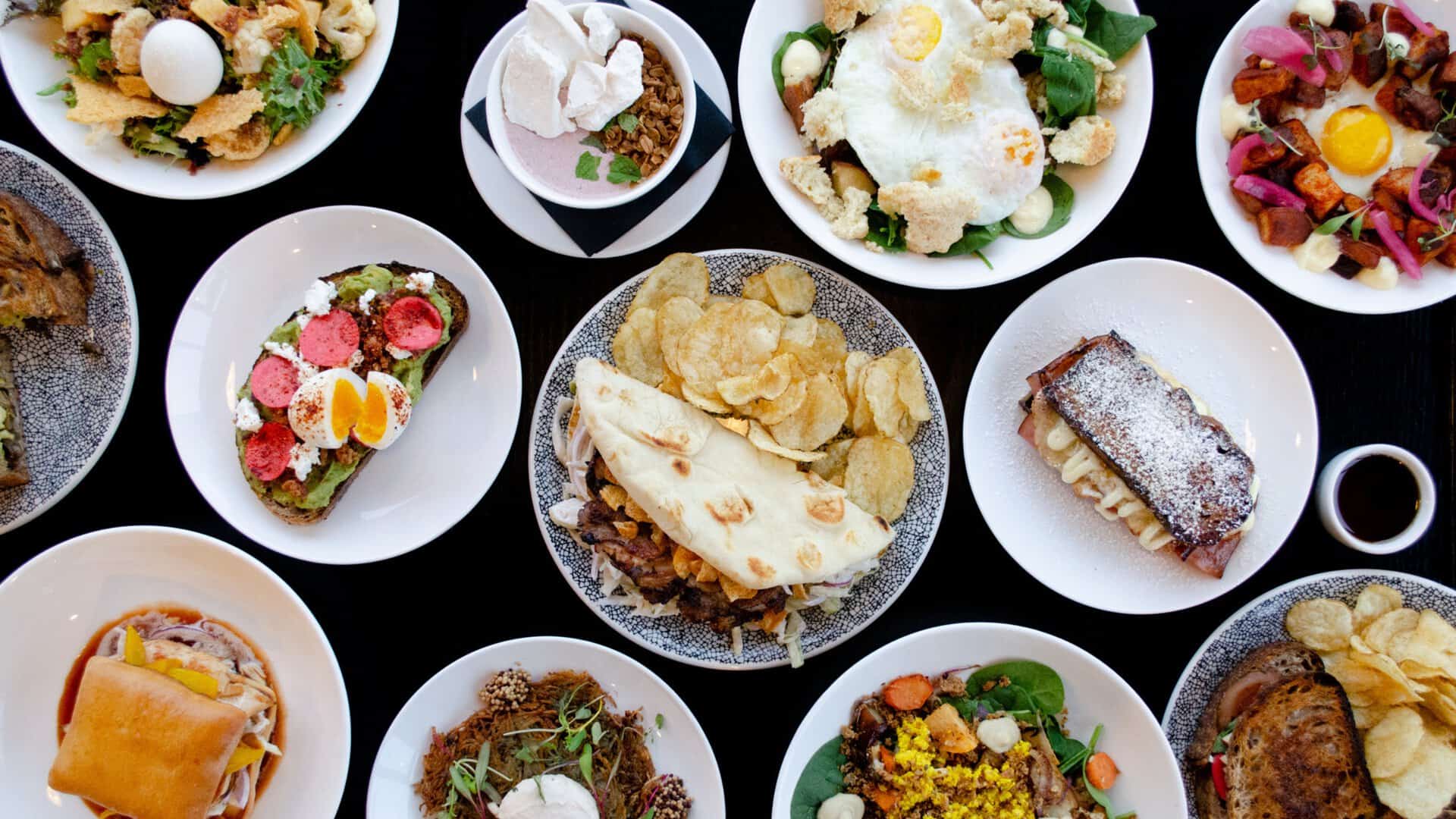 Colorful assortment of gourmet dishes including salads, desserts, and main courses on elegant white.