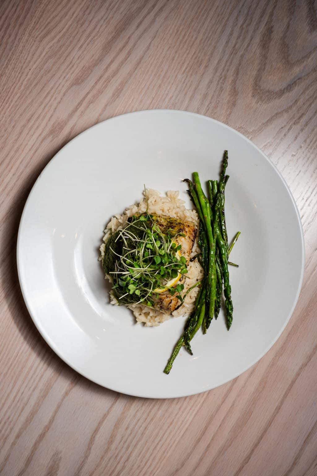 Black cod fillet served with asparagus and rice on a white plate.
