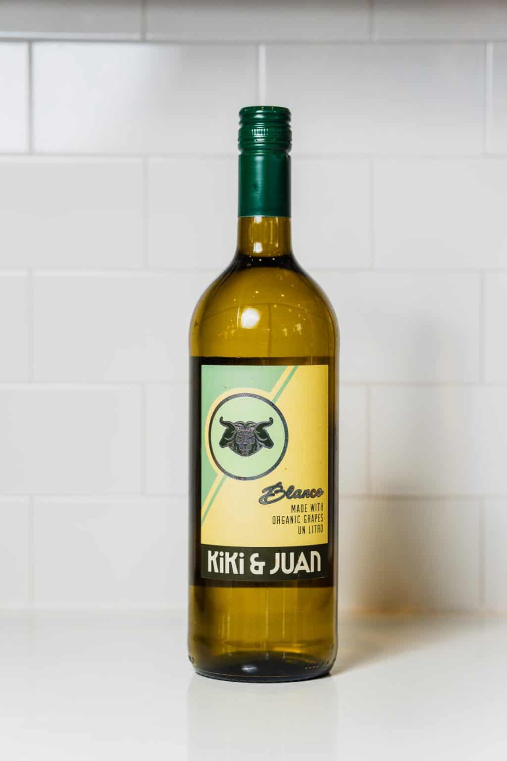 Kiki & Juad organic cannabis oil bottle on white surface with white tiled background.