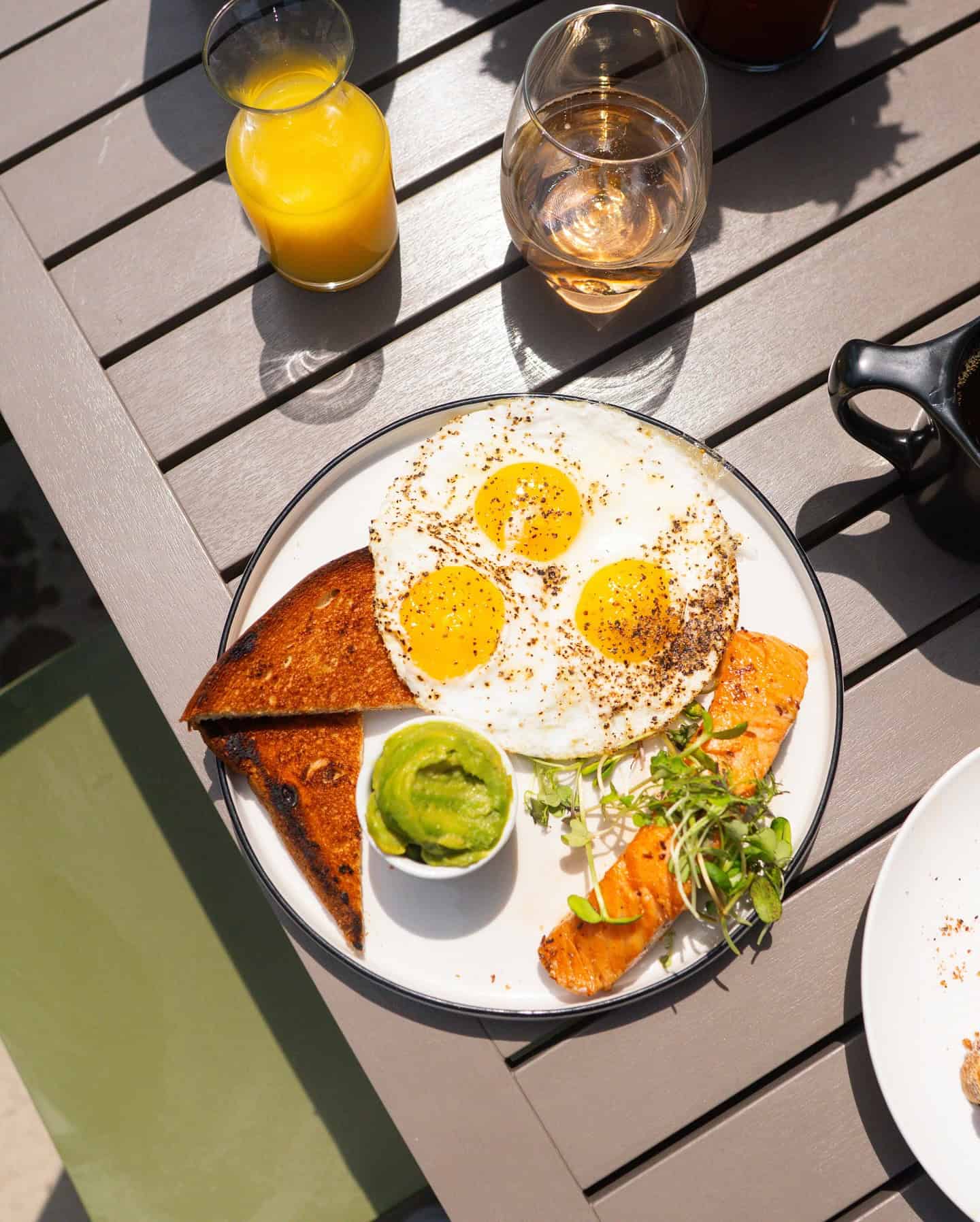 Eggs and toast with smoked salmon and avocado on a breakfast plate.