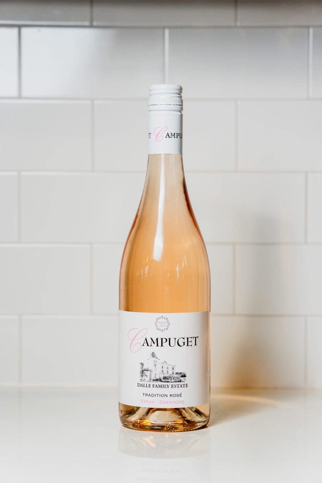 Campuget rosé wine bottle on a kitchen counter with white tiles.