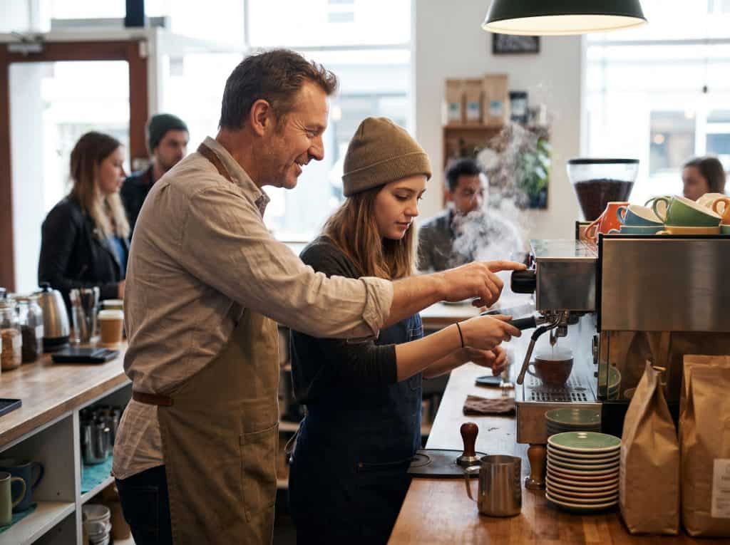 Barista preparing coffee in a busy cafe setting, focus on quality and service.