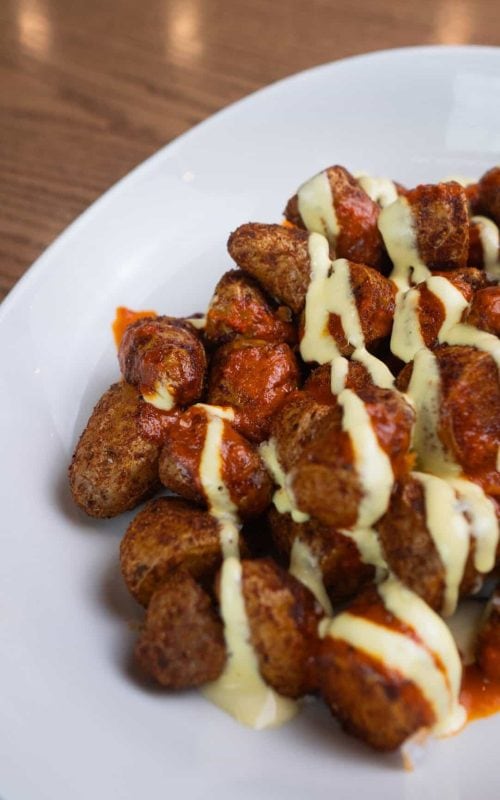 Delicious fried bites topped with creamy sauce, served on a white plate at Spring Lake.