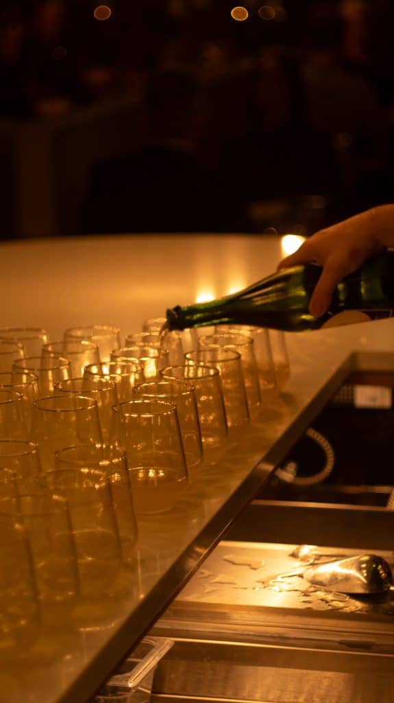 Pouring drinks at Mudpenny bar with glasses on a counter.