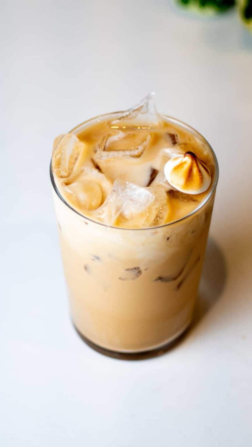 Iced coffee with cream and ice cubes, served in a clear glass.