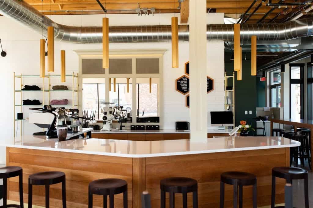 Contemporary coffee shop interior with barista station and seating area for customers.