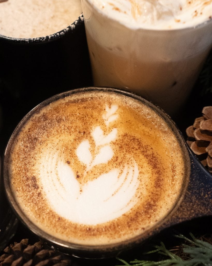 Latte with leaf-shaped foam art in a black cup.