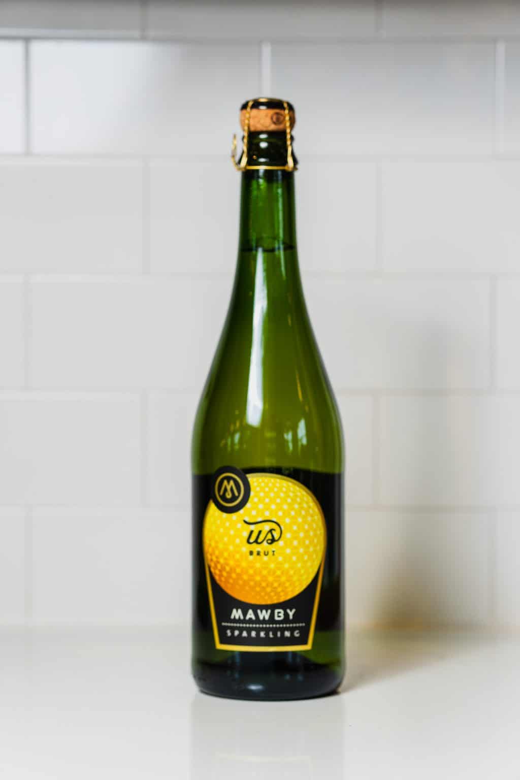 Green glass bottle of Mawby sparkling fruit drink on white background.