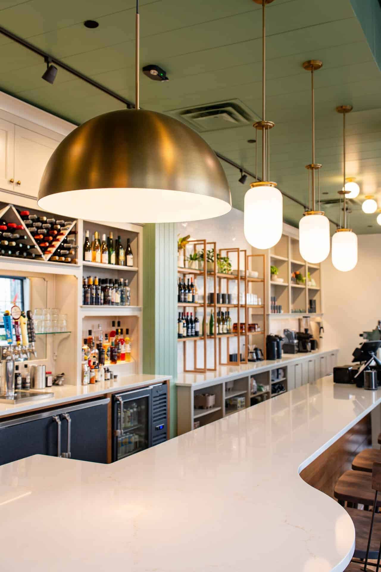 Stylish bar interior with wine bottles, pendant lights, and a white marble counter.