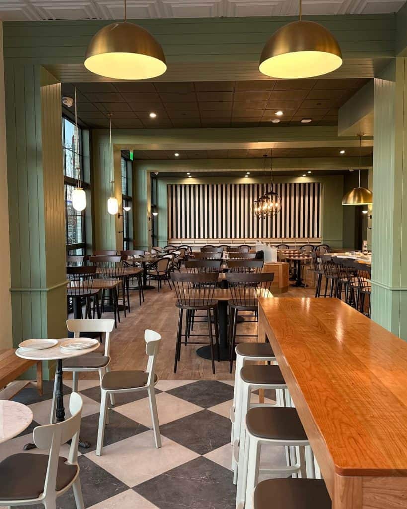 Stylish restaurant interior with green walls, wooden accents, and modern lighting.