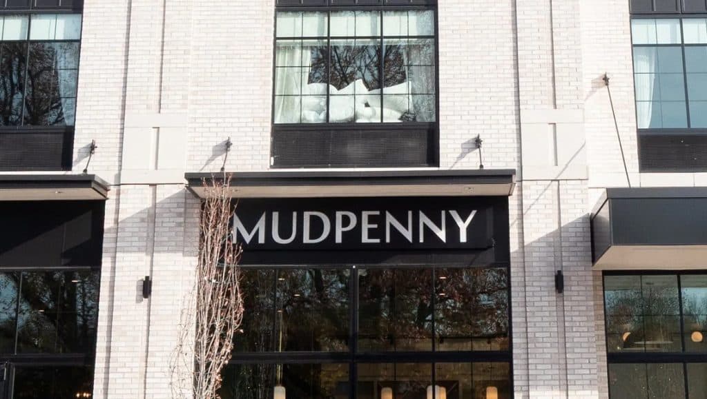 Mudpenny retail store entrance with modern architecture and signage.