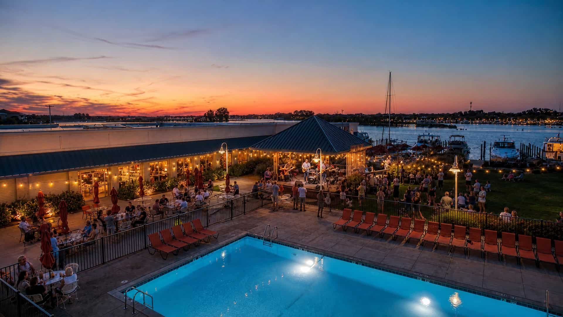 Outdoor live music event at Mudpenny with sunset view over the marina.