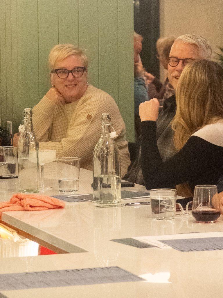Group of people enjoying a dinner conversation at a cozy restaurant.