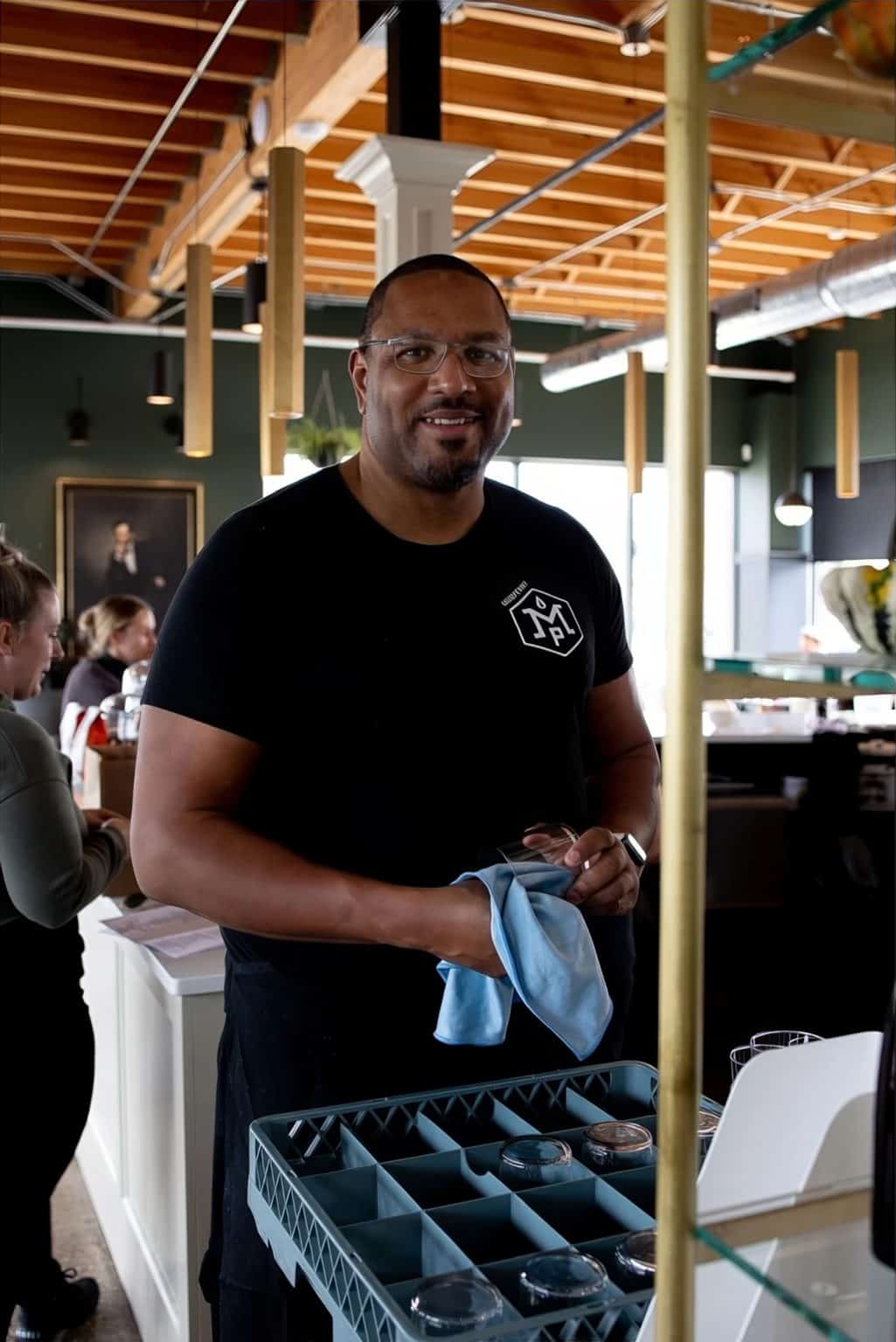 Smiling staff member holding a cloth in a modern restaurant setting.