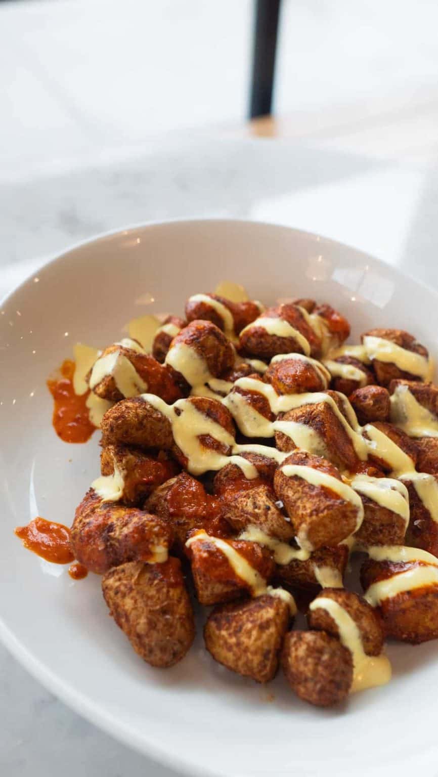 Delicious cheesy meatballs drizzled with creamy sauce, served on a white plate for a savory appetize.