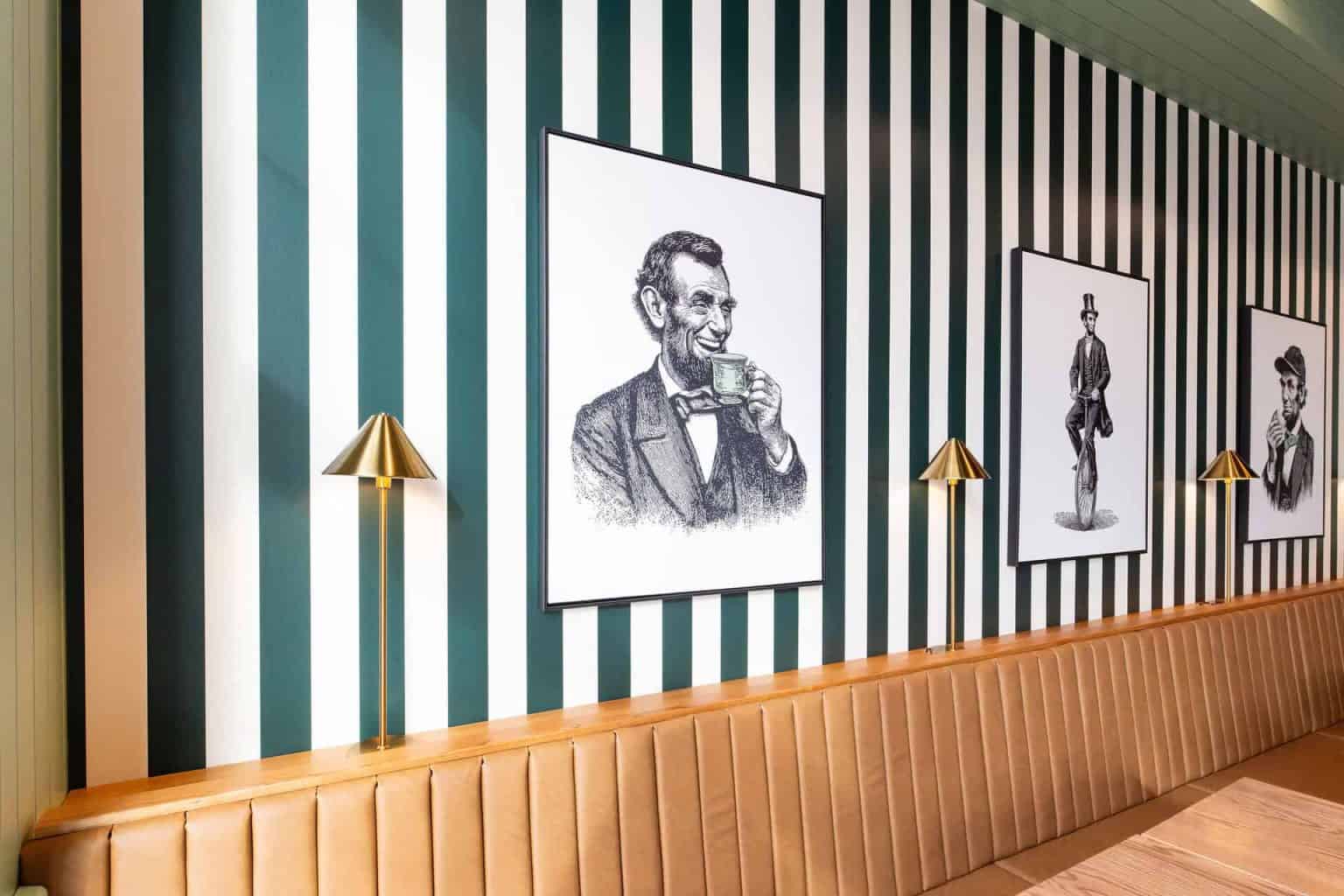 Stylish coffee shop interior featuring vintage artwork, striped wallpaper, and cozy leather seating.