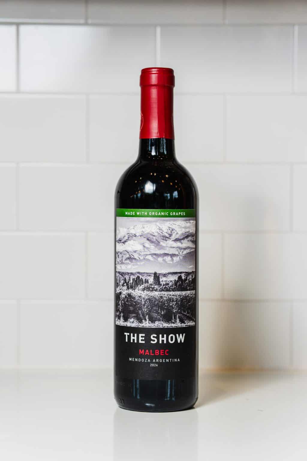 Malbec wine bottle with scenic label and red cap on white background.