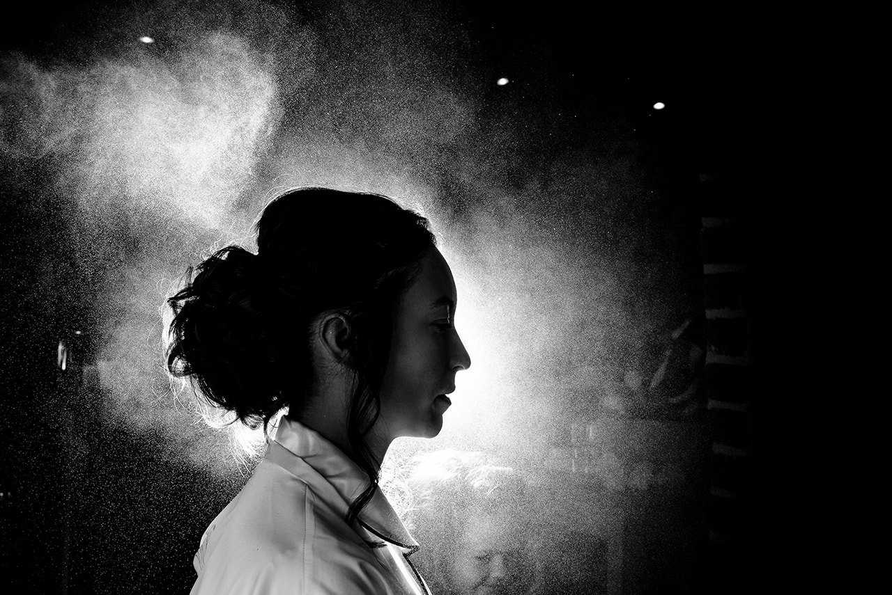 Documentary wedding photo flash lit hair spray silhouetting bride during wedding morning preparations one thousand words Lulworth Estate