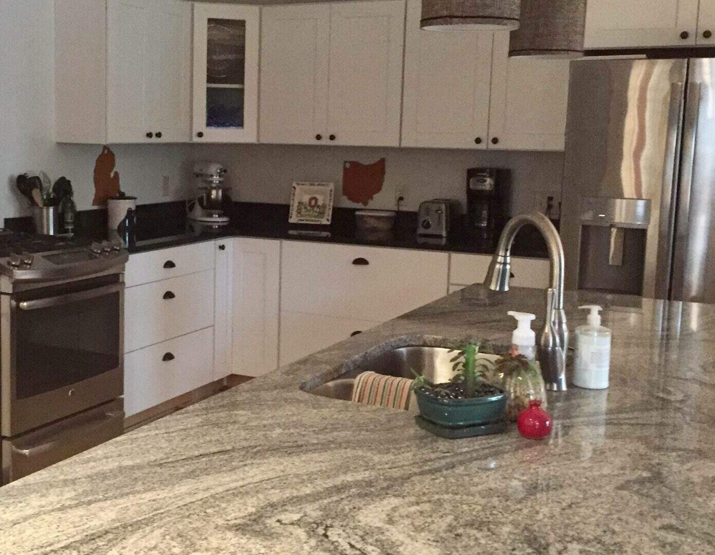 Close-up of a granite kitchen island with sink and soap dispensers.