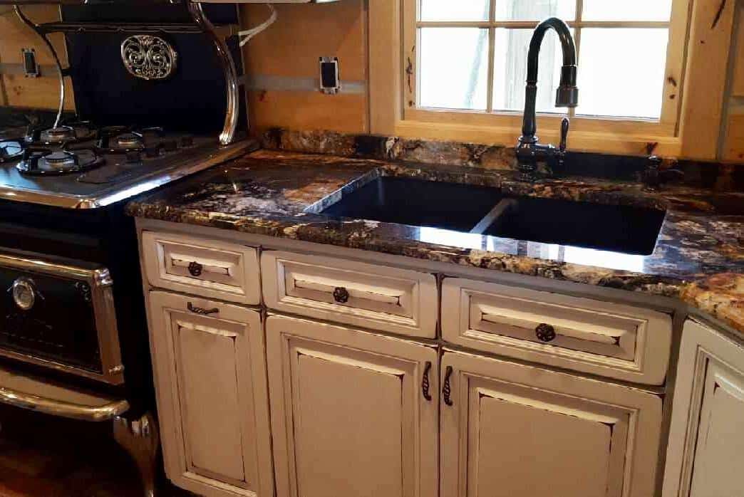 Black granite kitchen countertop with double sink and wooden cabinets.