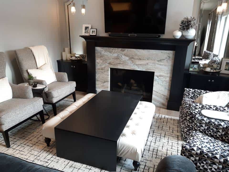 Living room with granite fireplace, sofa, armchairs, and TV.