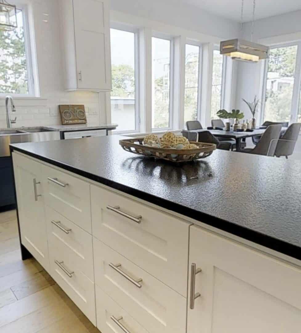 Bright kitchen with white cabinets and black granite countertop.