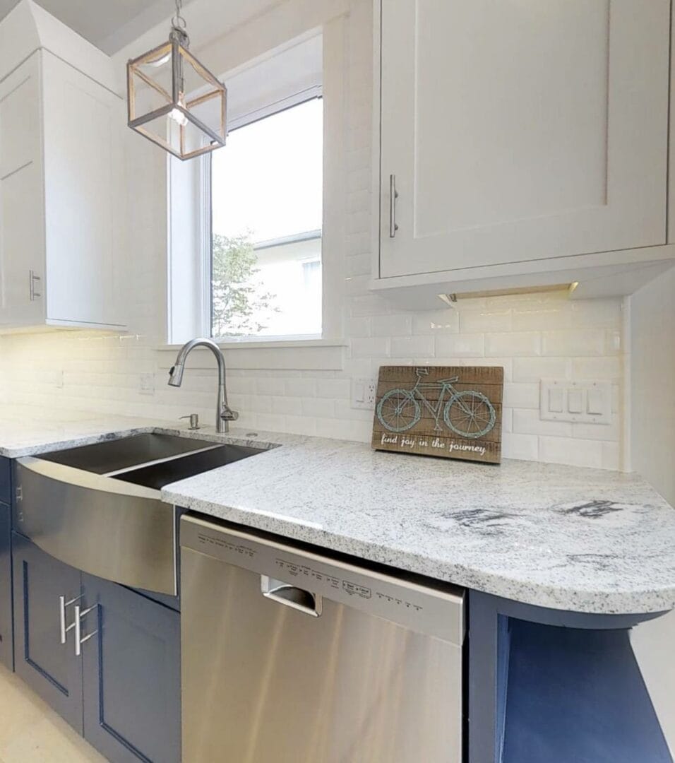Kitchen with granite countertop, stainless steel sink, and white cabinets.