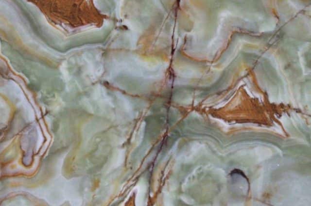 Close-up of polished natural stone granite with green, brown, and white veining.