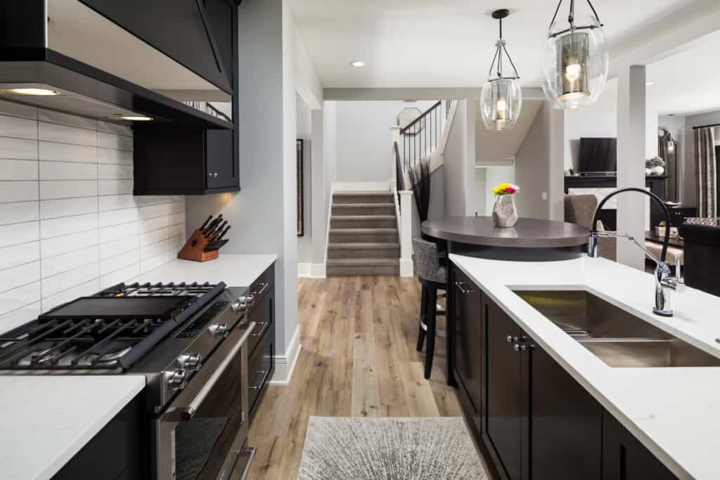 Contemporary kitchen with black cabinets and white granite countertops.