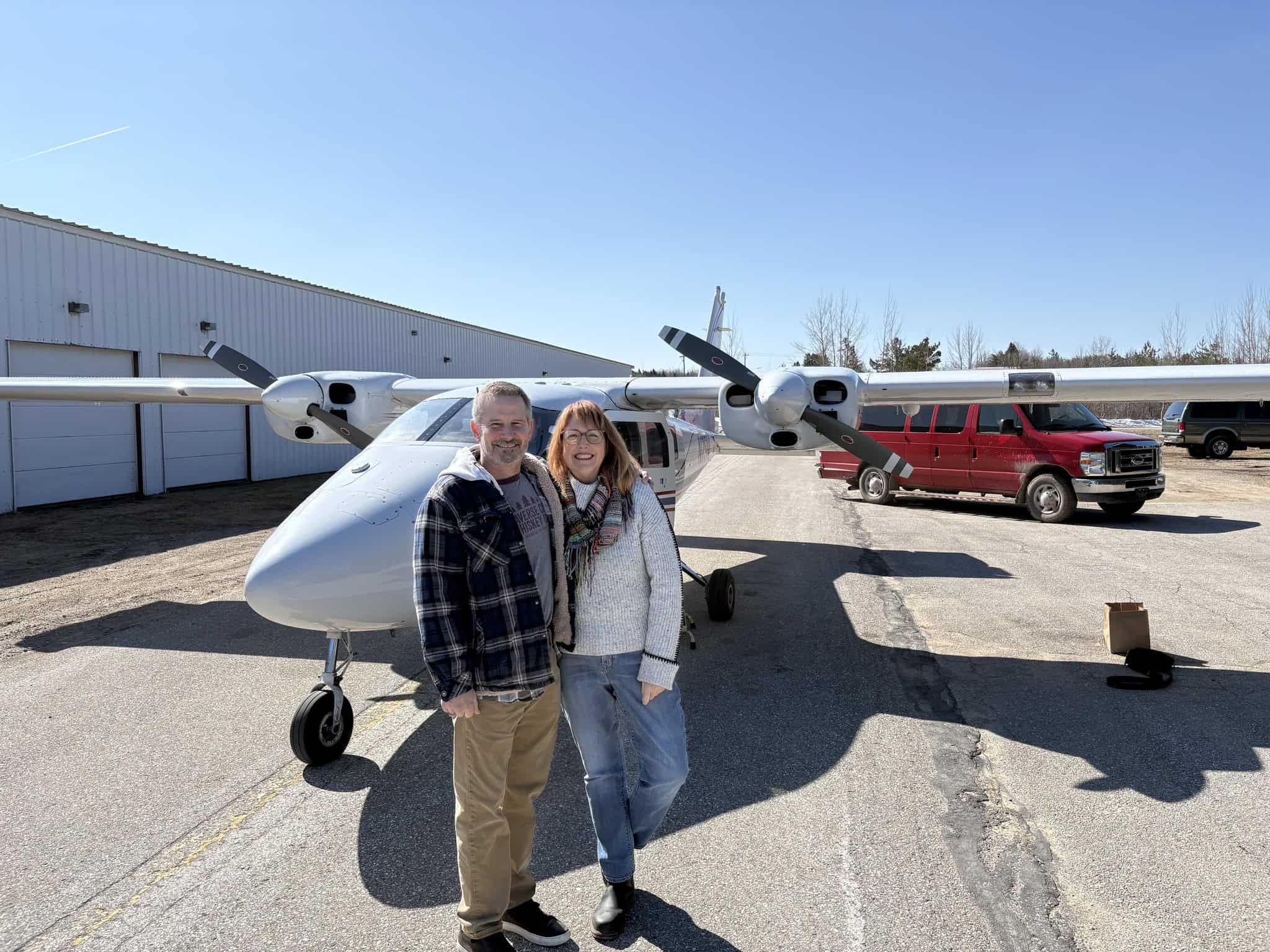 Two people standing in front of a small private plane at Rock Solid Granite.