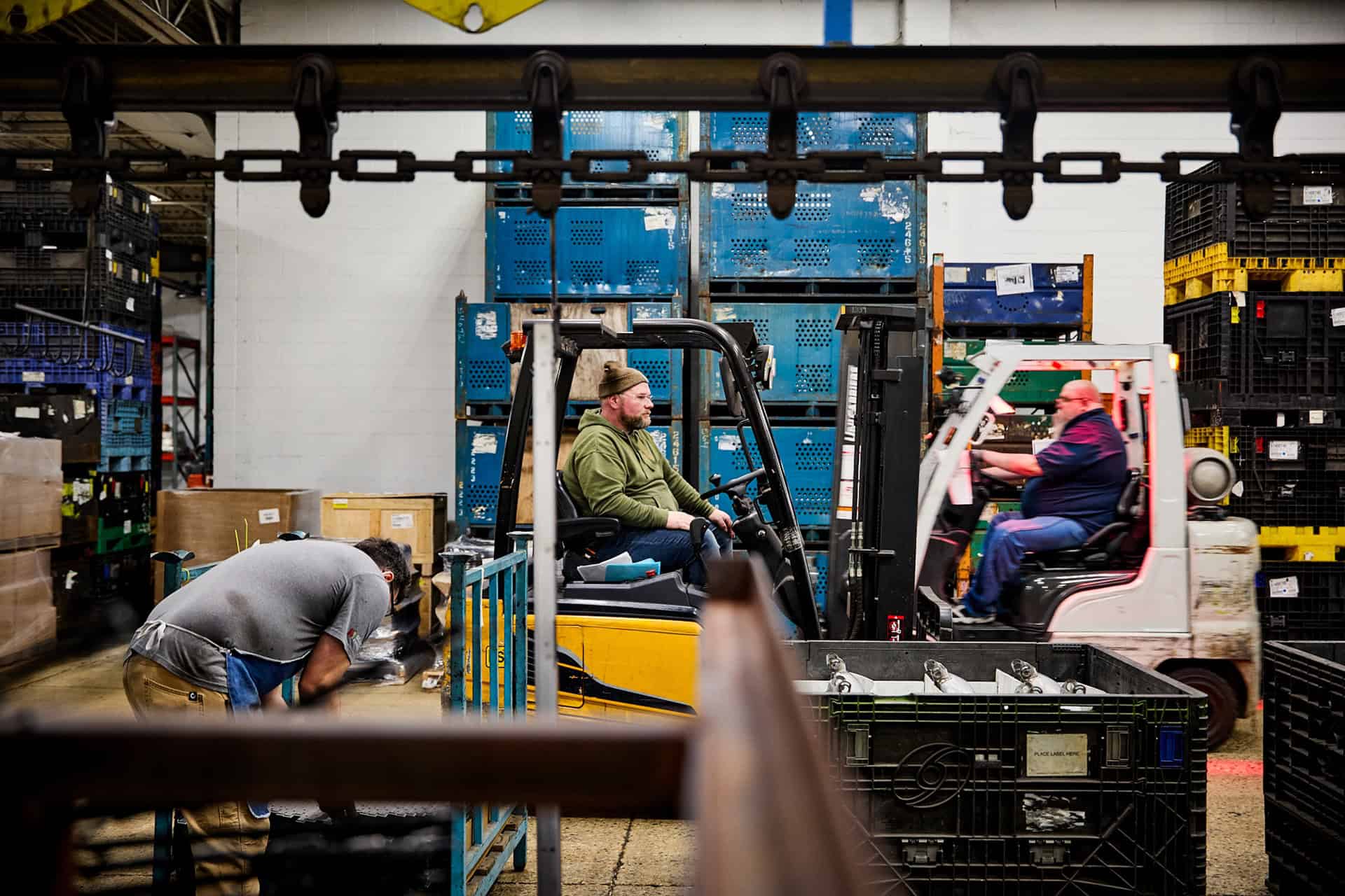 Warehouse workers using forklift in industrial storage facility.