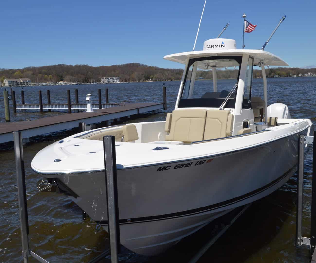 Powerboat docked at marina with water and shoreline in background.