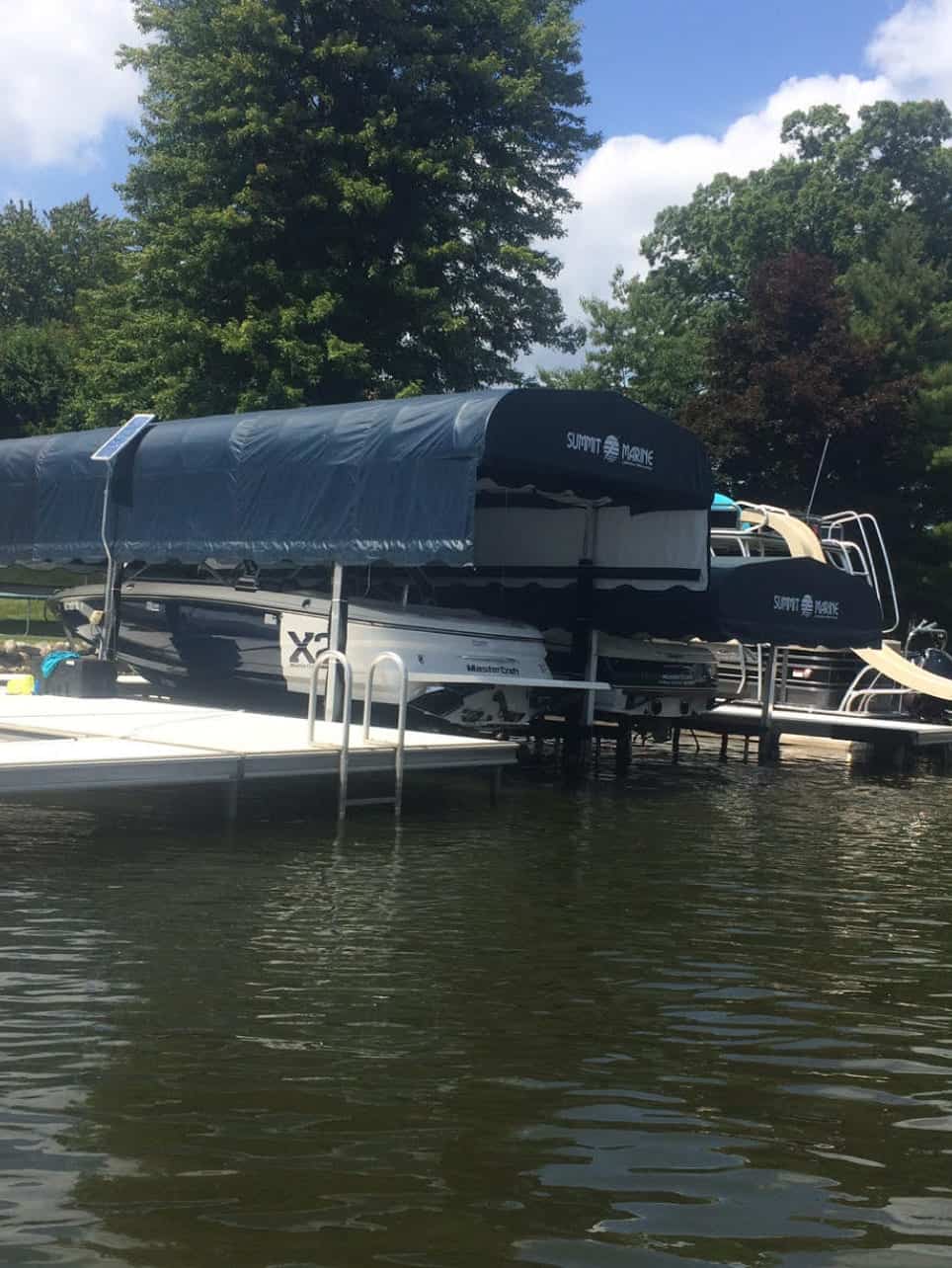 Pontoon boat with a black canopy docked on the water.