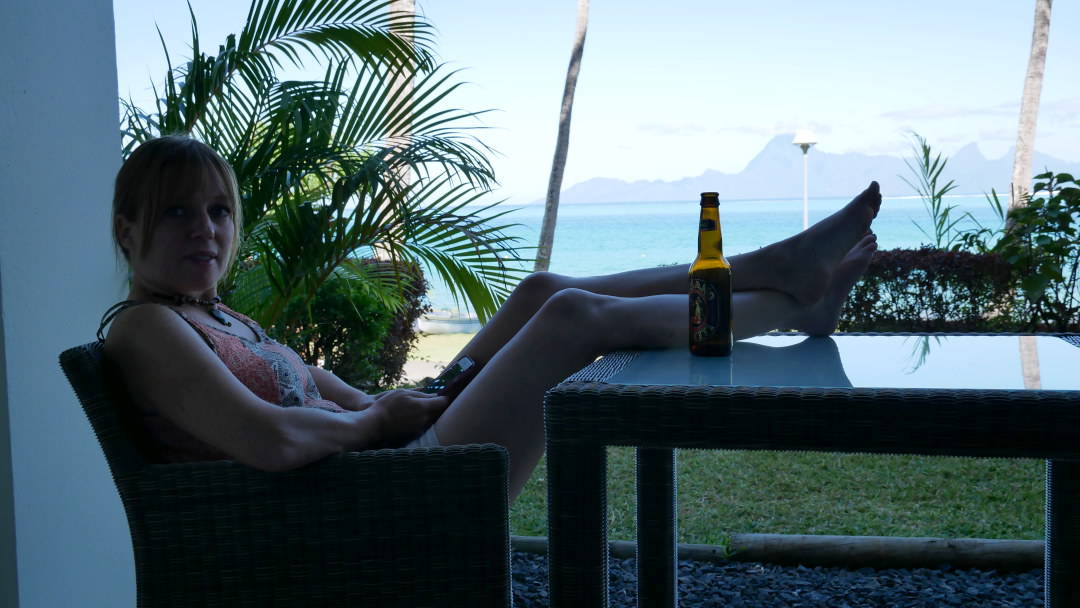 Emily with her feet up at the table with a beer overlooking the water in Tahiti